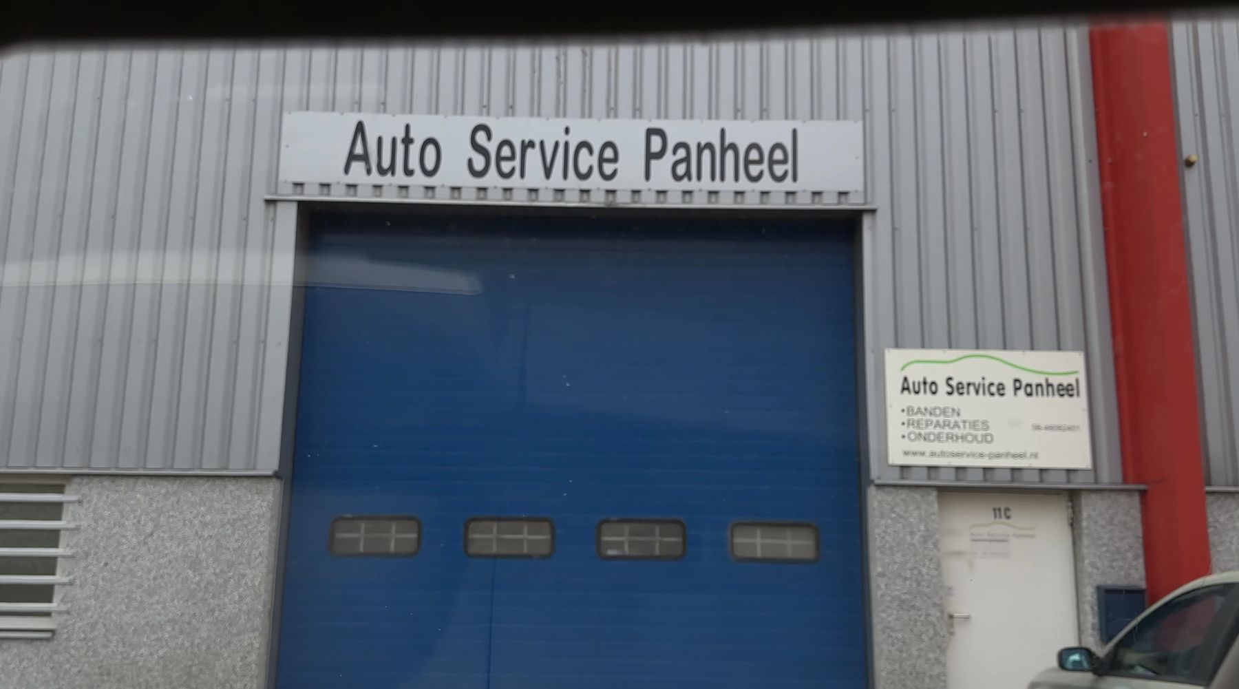 De gevel met het bord Auto Service Panheel boven de blauwe roldeur