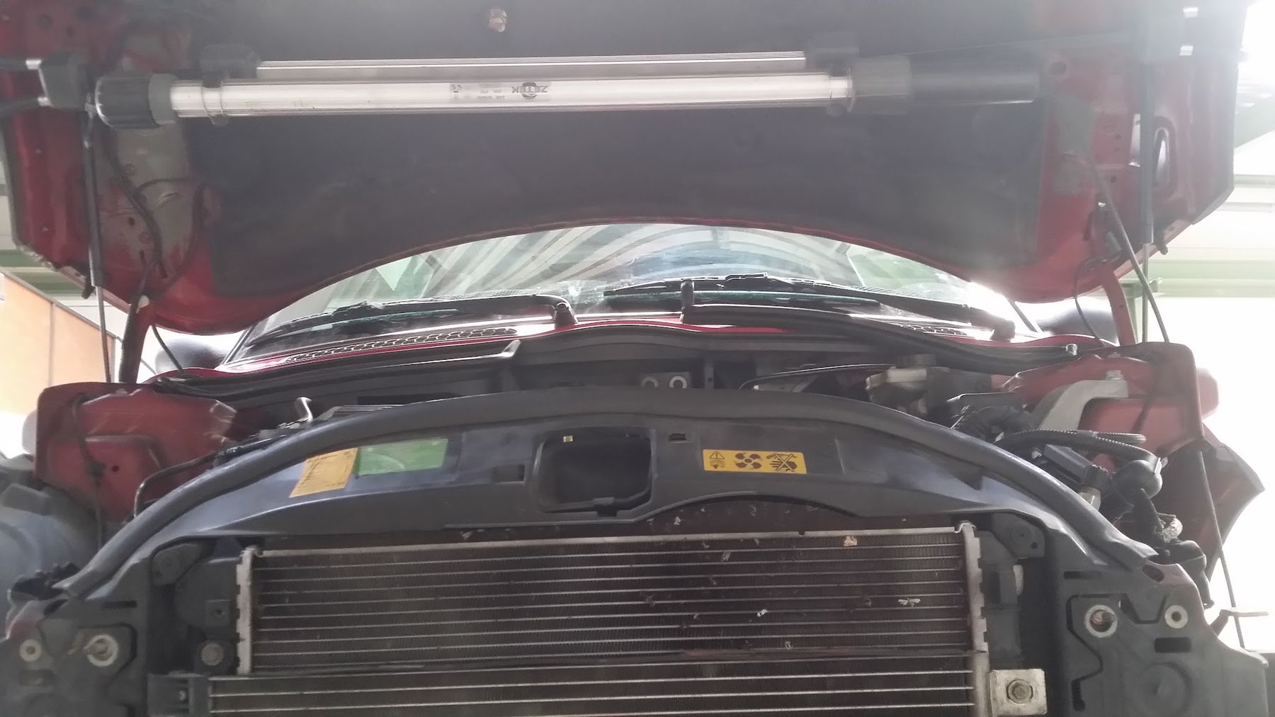 Een rode auto met de voorkant eraf, de radiateur zichtbaar